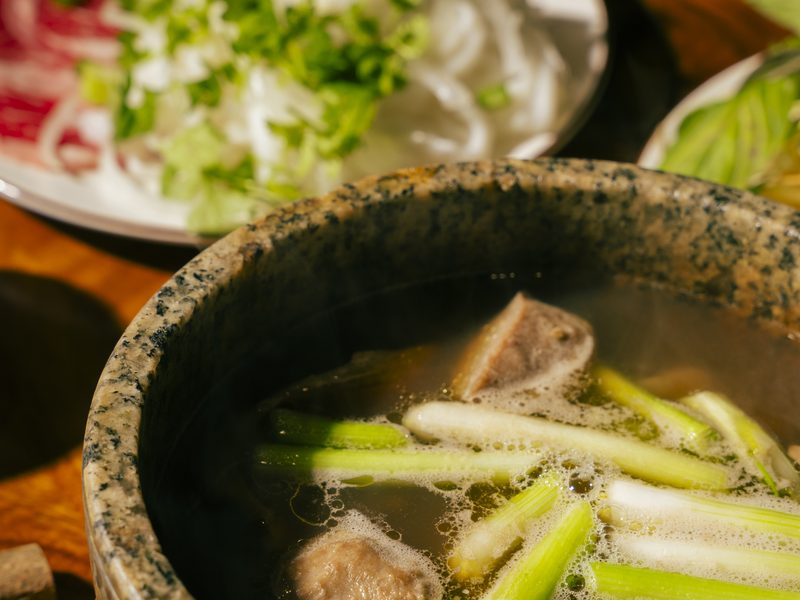 Stone bowl arriving at the table still steaming, rare beef and herbs alongside
